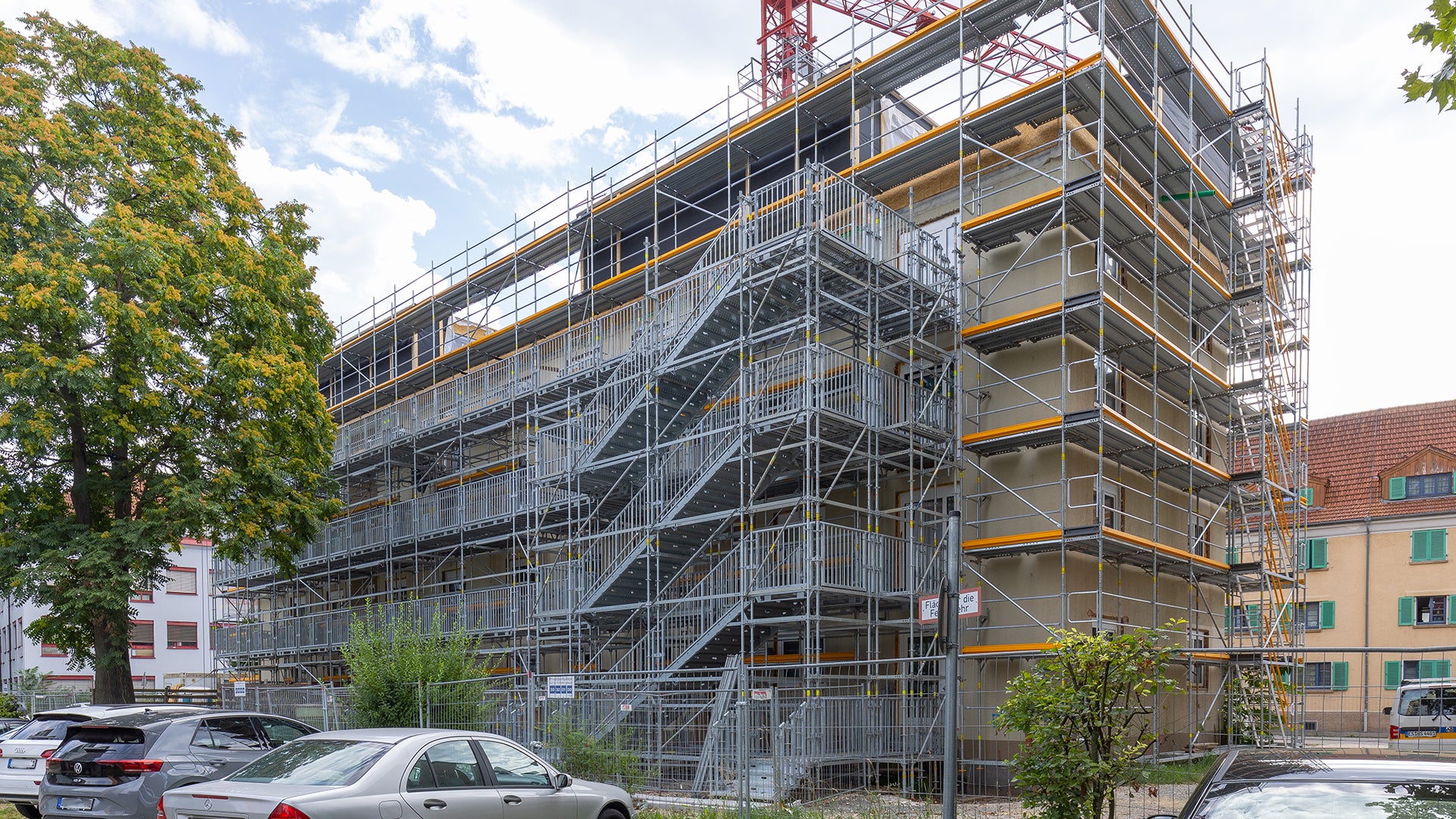 Ein 10 m hoher Treppenturm mit 35 m langen Laubengängen auf Basis der PERI UP Public Gerüstlösung macht gartenseitig alle vier Wohnebenen für die Bewohner während der Baumaßnahme zugänglich.