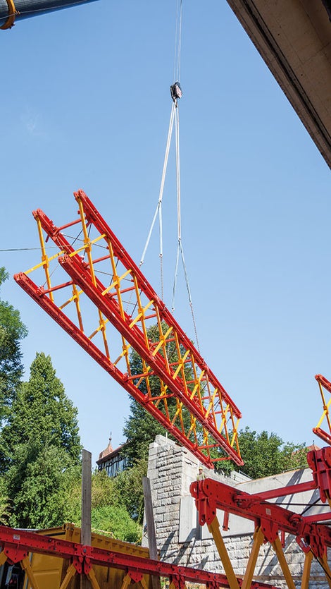Modular shoring assembly: VARIOKIT system components were pre-assembled on the ground to form truss segments and placed into intermediate storage with the crane. Three such segments were subsequently coupled to create a 37 m long truss unit and lifted over the Mur by means of a mobile crane.