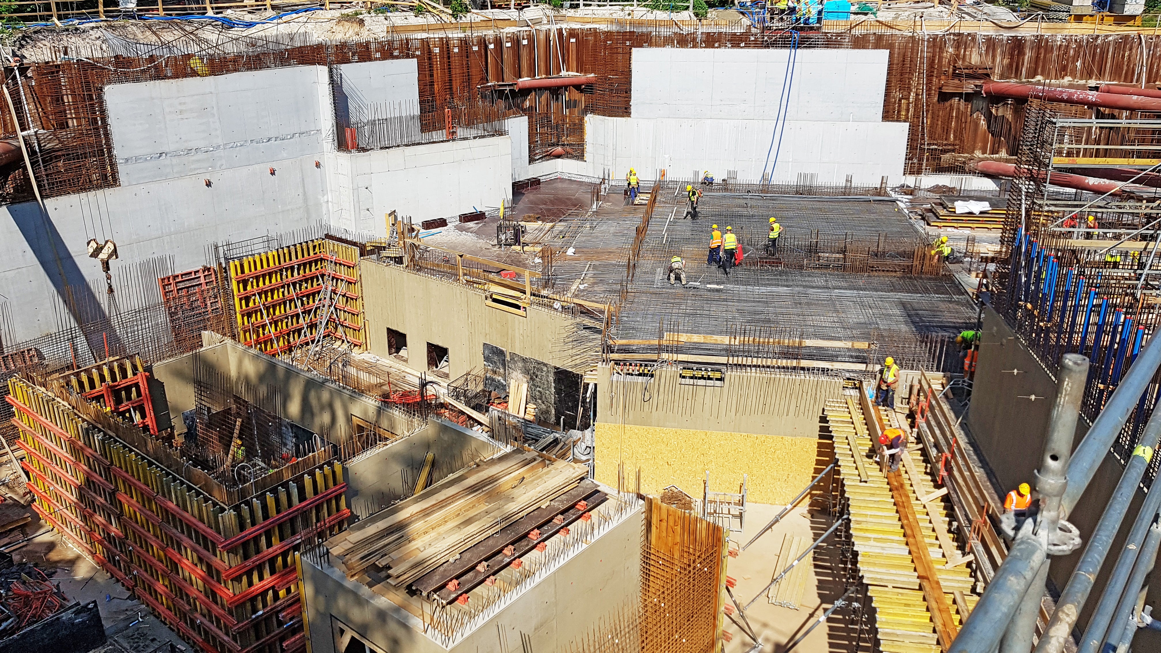 Deskowanie ścian klatki schodowej i holu na trzeciej kondygnacji podziemnej. Widoczny system ścienny VARIO VT 20K i wykonane ściany z odciskiem deski 20 cm. W tle - ściana osłonowa między rozparciami.