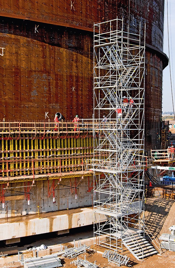 Stair tower with twin staircase units for the construction of a liquid gas tank. Guardrails mounted on the outer and middle stringers provide safe passage.