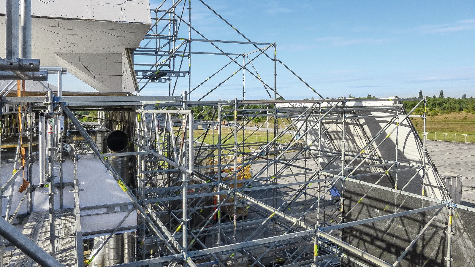 Částečné zakrytí vrchní části konstrukce a postranní věže pomocí vysunutí s diagonál a příhradových vazníků.
