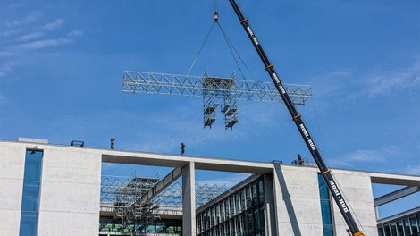 Nach der Fertigmontage am Boden lassen sich die 24 m langen und 2,50 m breiten PERI UP Gerüsteinheiten mit dem Mobilkran auf das Dach einheben und anschließend von Hand nach innen hin verfahren.