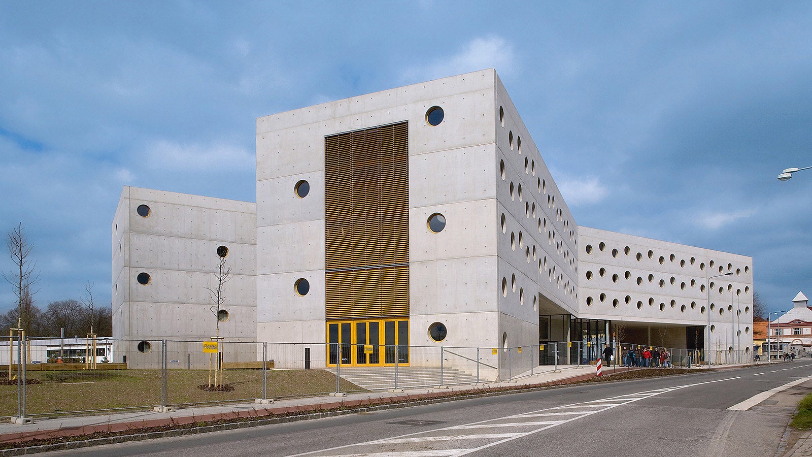 Cu o amprentă în formă de X, conceptul arhitectural al acestei clădiri a creat un nou punct de atracție în dezvoltarea orașului Hradec Králové. Inițial, toate fațadele ar fi trebuit să aibă un finisaj de vopsea culoare orange. S-a renunțat însă la concept urmare a calității suprafeței de beton obținute. 