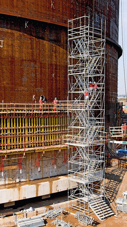 Stair tower with twin staircase units for the construction of a liquid gas tank. Guardrails mounted on the outer and middle stringers provide safe passage.