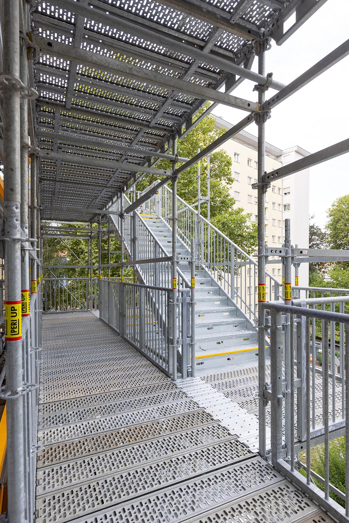 Jeweils zwei hintereinander angebrachte Treppenläufe machen die im Höhenraster von 3,00 m angeordneten Laubengänge zugänglich.