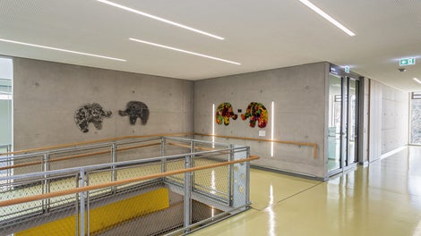 Die offen gestalteten Flure sowie die Treppenhäuser und Rollstuhlrampen weisen eine markante Sichtbetonoptik auf.