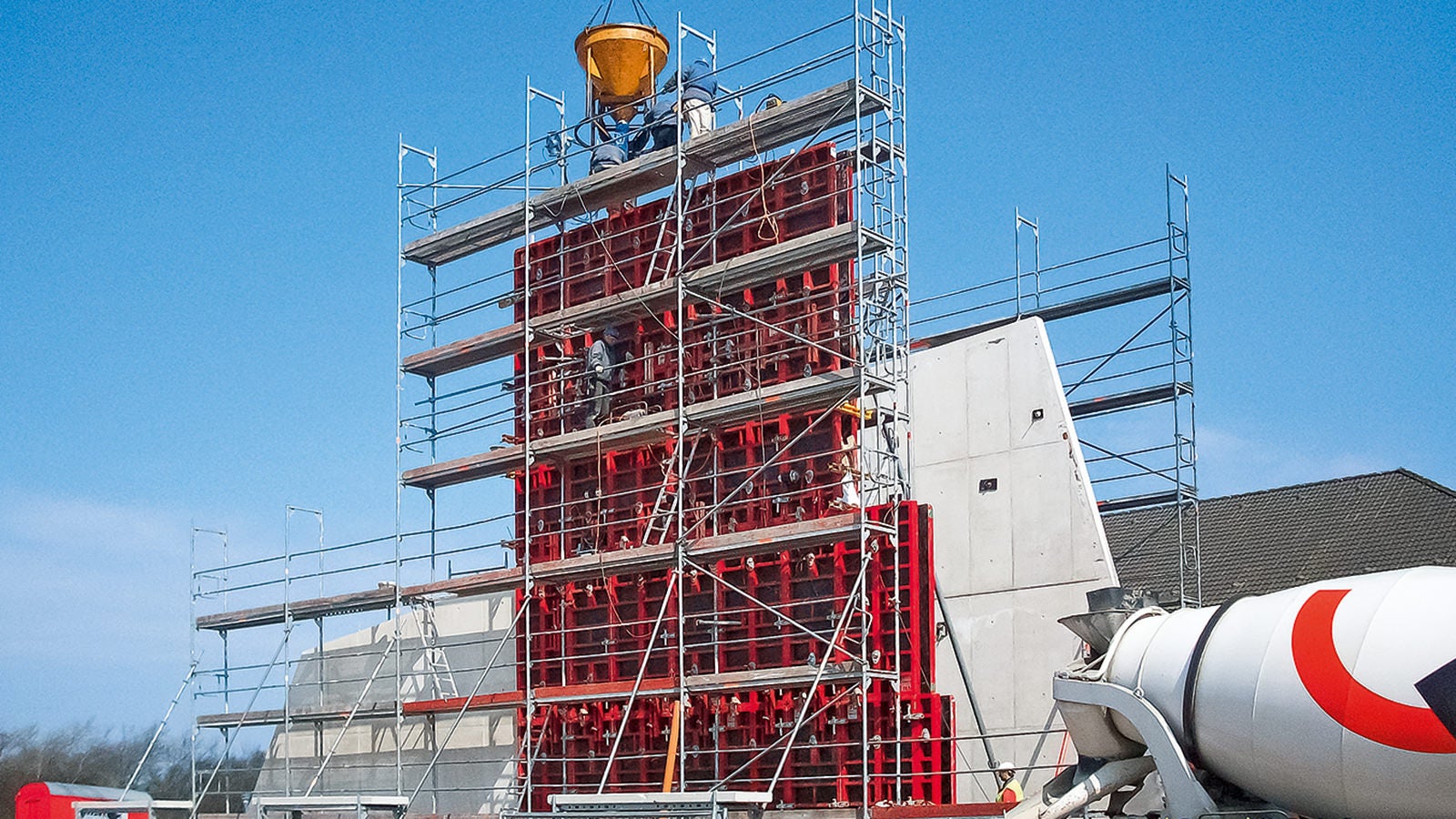 Auf der Landseite der Weißbeton, auf der Seeseite der metallische Körper – das ist die architektonische Idee, das Thema "Verbindung" auch mit der äußeren Gestaltung darzustellen. Auf halber Wandhöhe wird eine Betonierfuge eingeplant – ausgeführt mit einer Dreikantleiste.