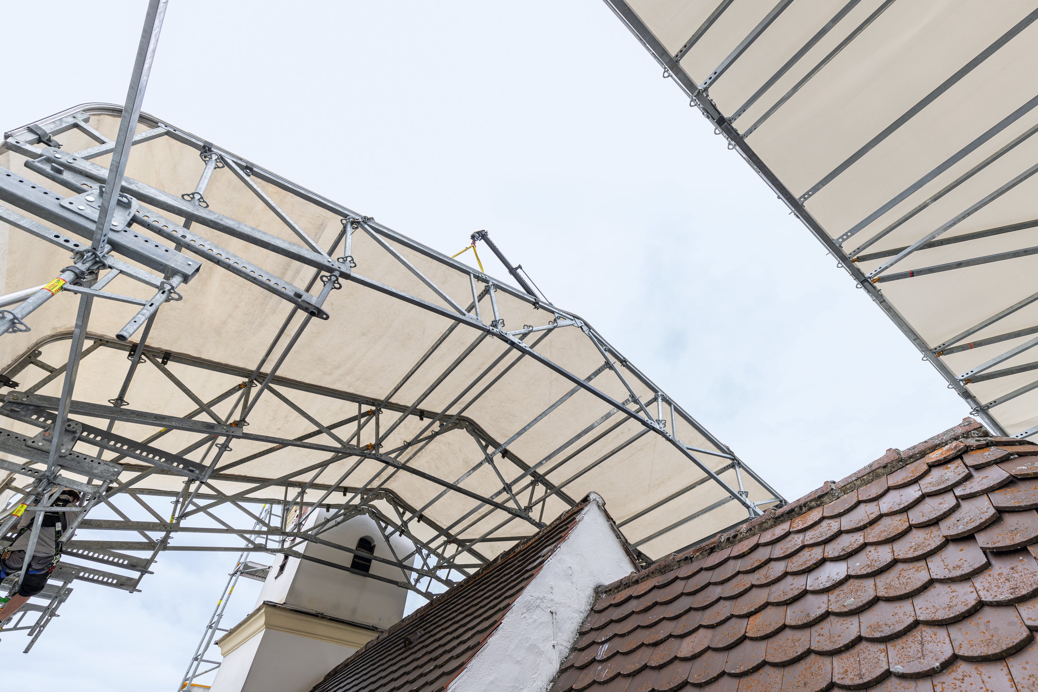 Mit dem zweiten Kranhub wird die 5,75 m breite Dacheinheit an einem Stück zum westlichen Turm hin angesetzt.