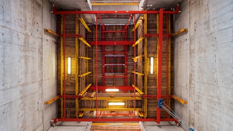 ACS-P - часто применяемый вариант, когда шахта опережает перекрытии нижних этажей<br/>Платформа образует широкие складски подмости для арматуры и материалов<br/>Установка укрупненной арматуры возможна только частично или невозможна, так как стальные ригеля ACS-P пересекают в плане стены. Перестановка наружной и внутренней опалубки производится на всей захватки одновременно.