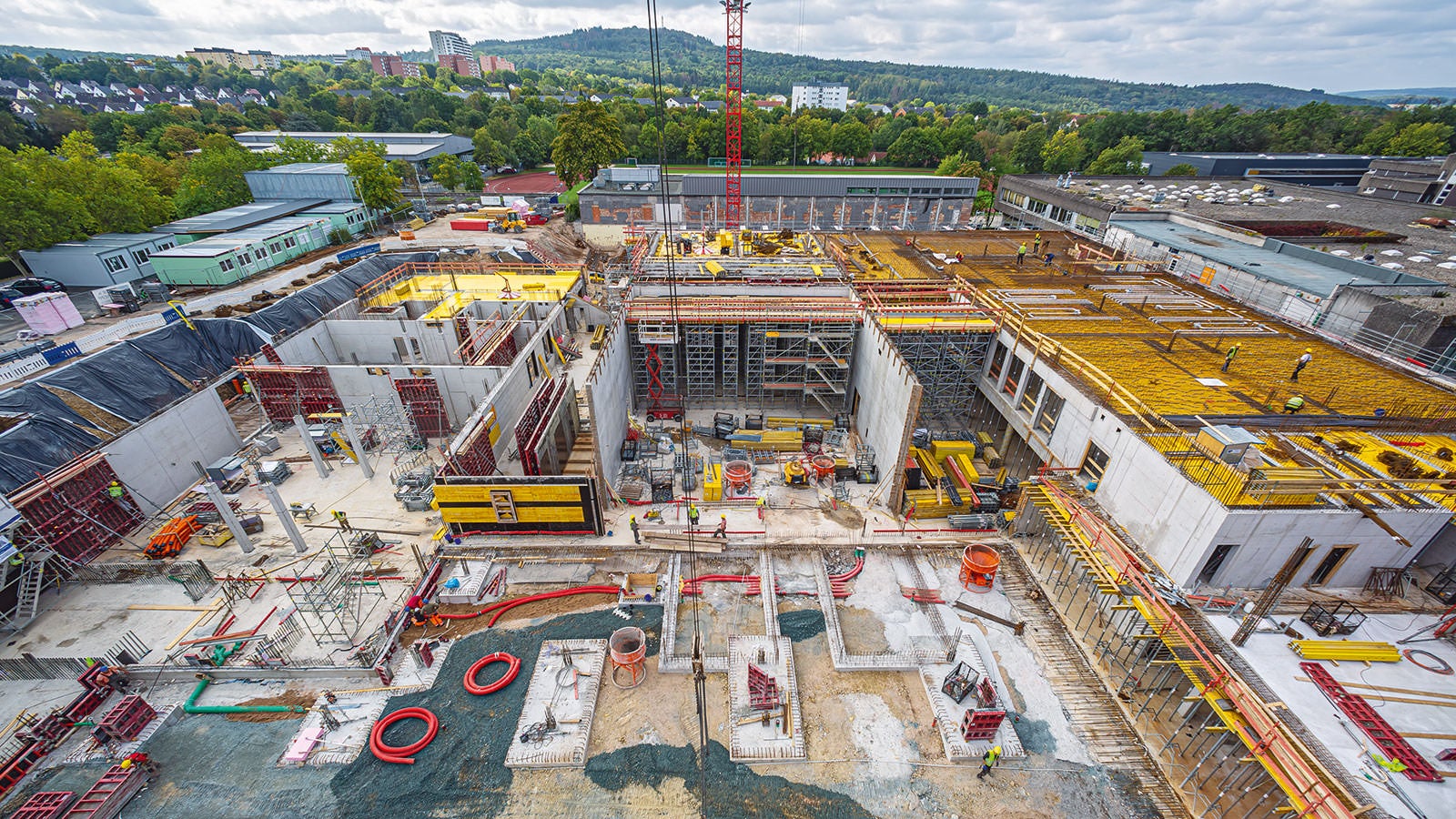 Das in massiver Stahlbetonbauweise zu errichtende, knapp 20 m hohe Schulgebäude weist Raumhöhen bis 8 m und Deckenstärken zwischen 28 cm und 36 cm auf.