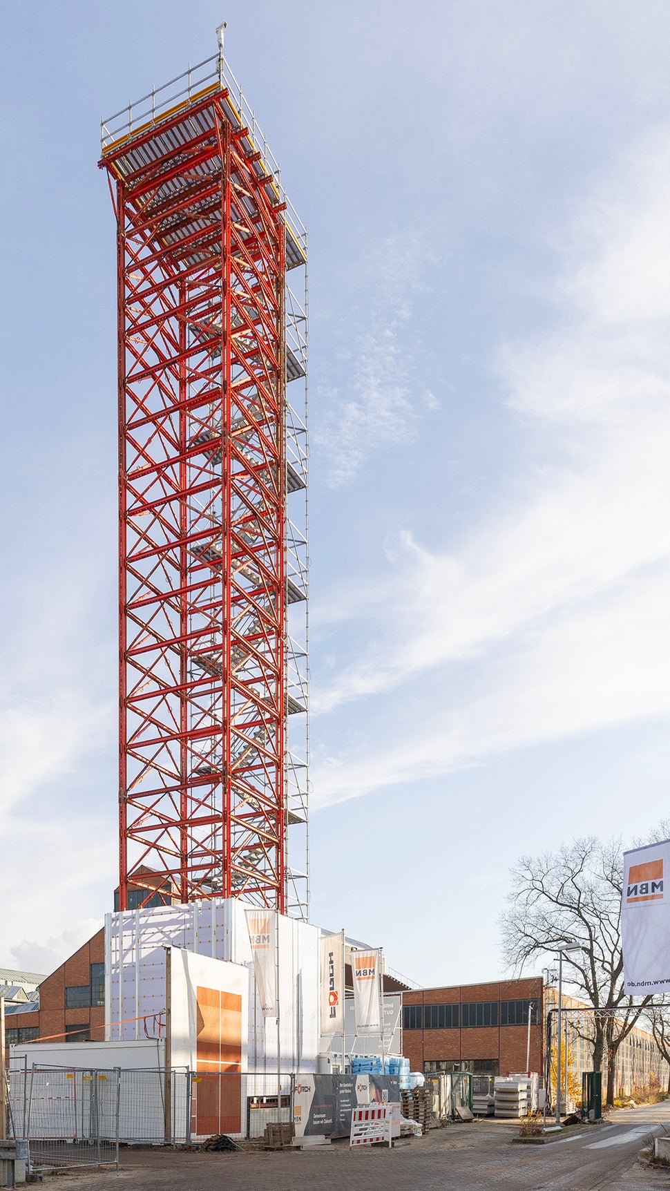 Der seitlich angebaute PERI UP Treppenturm mit 1,00 m Stufenbreite führt sicher und bequem bis zur Plattform in 30 m Höhe, während eine umlaufende Sockel-Einhausung mit PERI UP Cladding den Zugang zuverlässig abschottet.