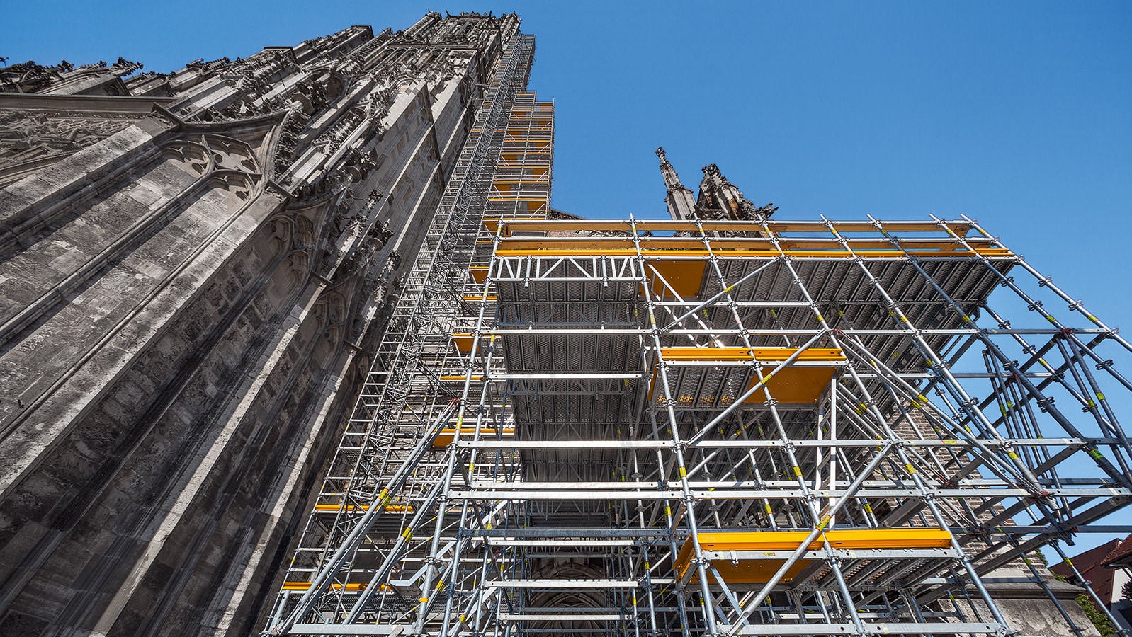 PERI UP nestles up to Ulm Minster - up to 71 m high - for the extensive renovation work. A 7 m high intermediate platform provides a possible storage location for the new stones.