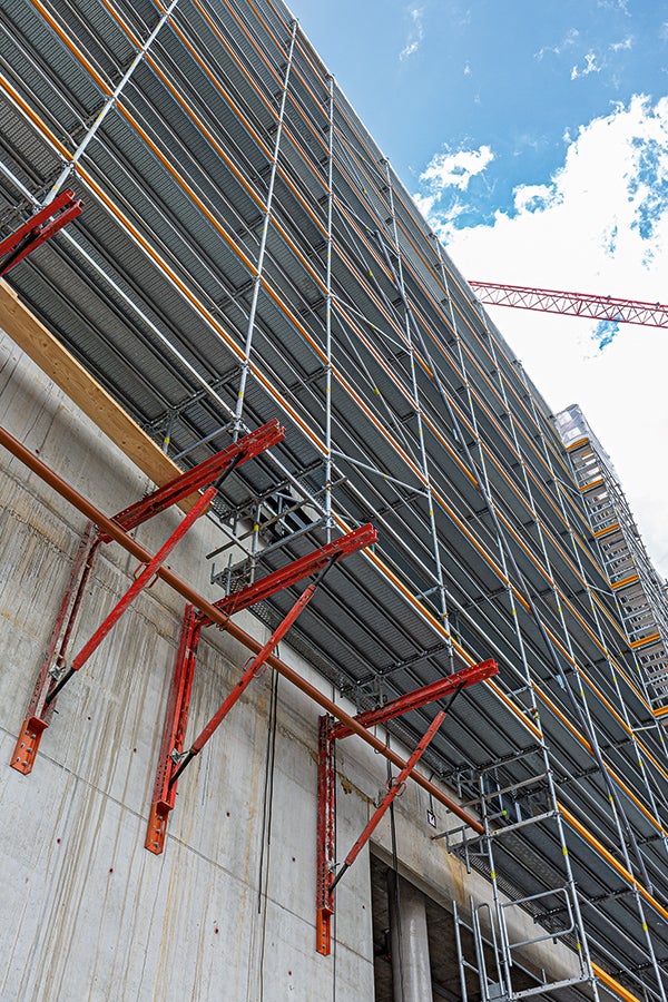 Kombinace v metrickém modulu: únosné konzoly ze základních dílů VARIOKIT podpírají fasádní lešení PERI UP všude tam, kde nemá podloží dostatečnou únosnost nebo je třeba ponechat volné plochy pro dopravu.<br/>(Foto: PERI Německo)<br/>