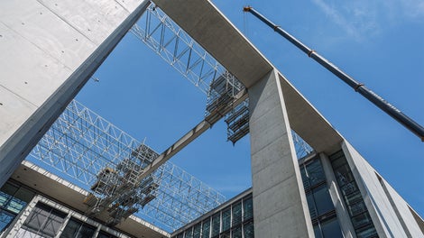 Pour les travaux de rénovation sur des fermes en béton exposées, un échafaudage suspendu mobile PERI UP enjambe le toit du bâtiment du Bundestag à Berlin.