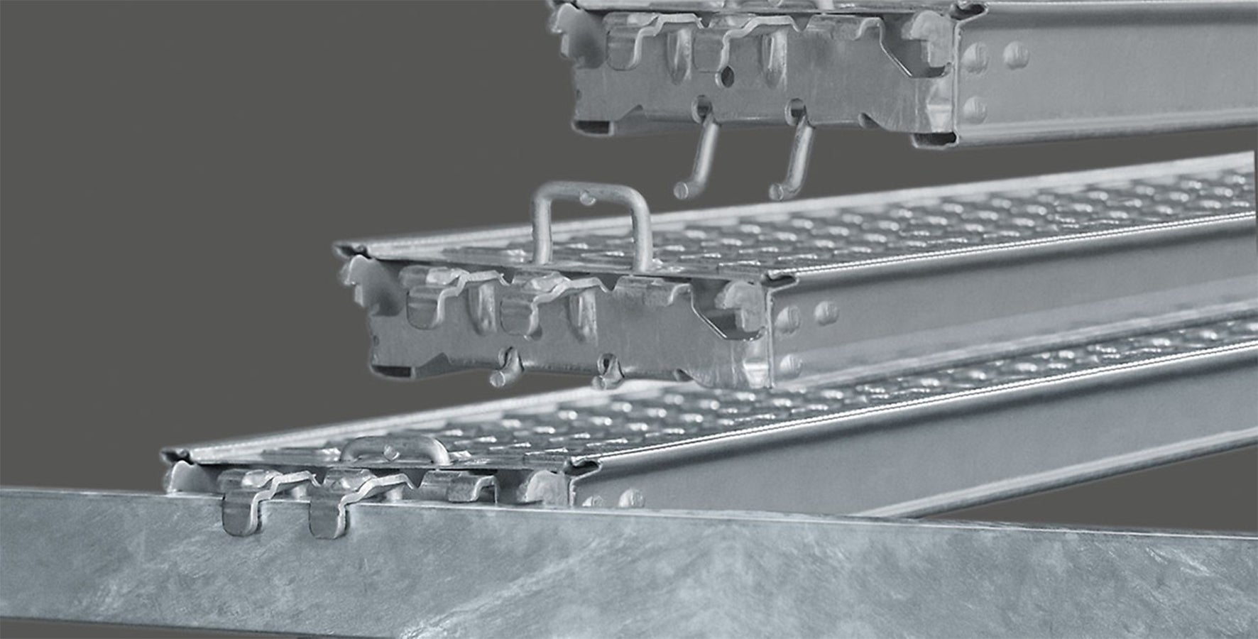 "Locking Deck"<br/>Podesty montuje się bezpośrednio na ryglach. Dodatkowy rygiel podtrzymujący podest nie jest konieczny. Pod wpływem siły ciężkości zaczep zatrzaskuje się, zabezpieczając podest przed przemieszaniem.